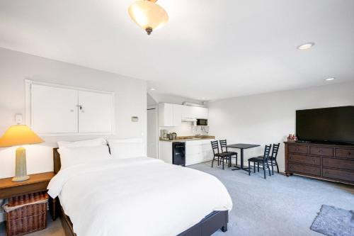 a bedroom with a large white bed and a kitchen at Garden Suite near Jericho Beach in Vancouver
