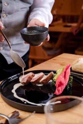 a person holding a spoon and a plate of food at Hotel Li Anta Rossa - Adults Only in Livigno