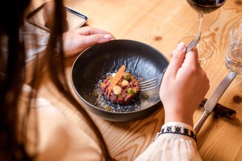 a person holding a fork and a plate of food at Hotel Li Anta Rossa - Adults Only in Livigno