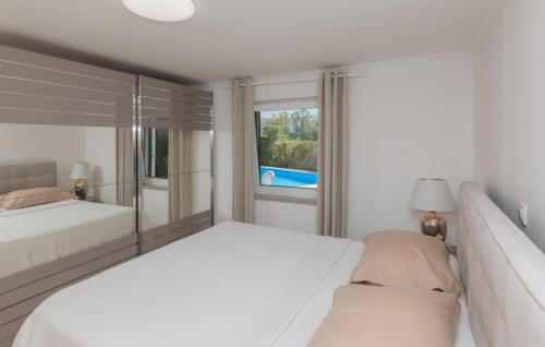 a white bedroom with two beds and a window at Beautiful Villa Lara with sauna in Imotski in Kamenmost