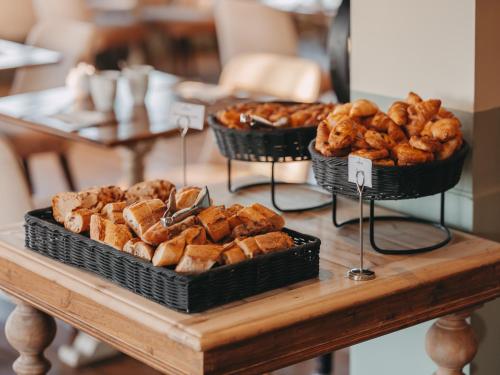 three baskets of bread and pastries on a table at Le Grand Large, Belle-Ile-En-Mer in Bangor