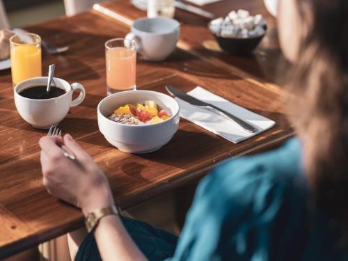 a woman sitting at a wooden table with a bowl of food at Le Grand Large, Belle-Ile-En-Mer in Bangor