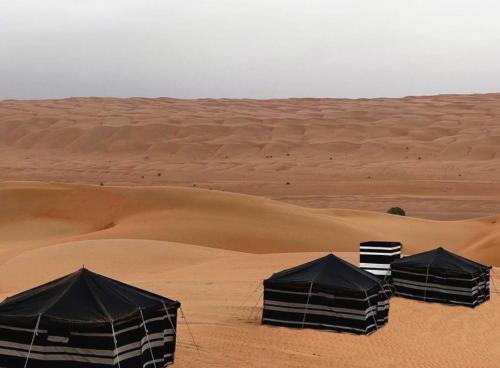 three black tents in a desert with sand at layali camp in Bidiyah