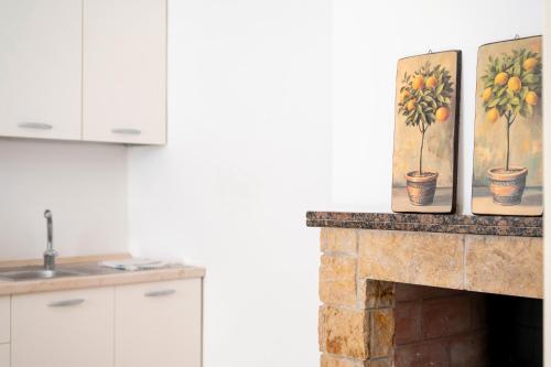 a kitchen with a fireplace with three paintings on it at Nel Cuore Del Salento Dimora Tipica in Calimera