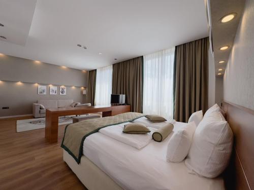a bedroom with a large white bed and a desk at Hotel Via Vitez in Vitez