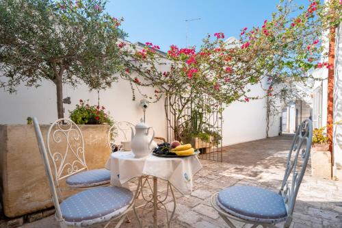 a table and chairs with a vase and fruit on it at Nel Cuore Del Salento Dimora Tipica in Calimera