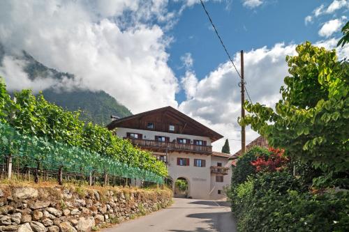 a building with a stone wall next to a road at Unterdornerhof Algund in Lagundo