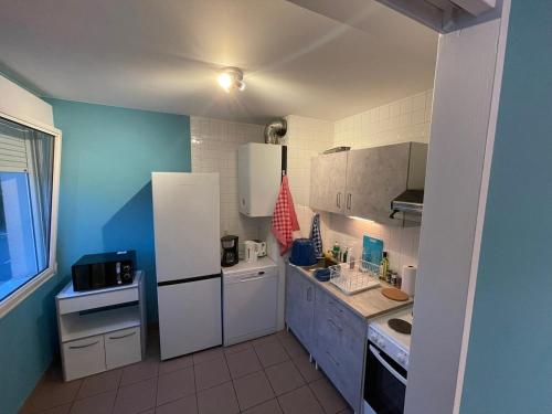a small kitchen with white appliances and blue walls at Magnifique logement hyper-centre-Paray-le-Monial in Paray-le-Monial