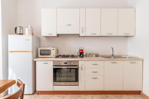 a kitchen with white cabinets and a white refrigerator at Nel Cuore Del Salento Dimora Tipica in Calimera