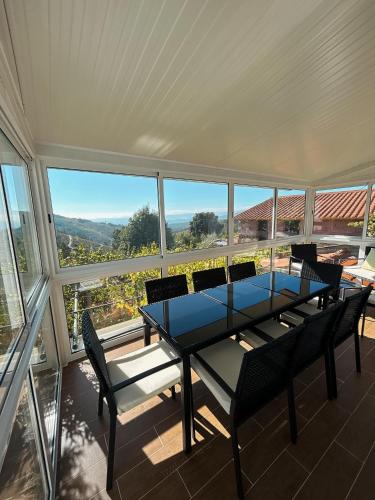 a dining room with a table and chairs and windows at Alojamento Local Vale dos Vascos in Alvaro
