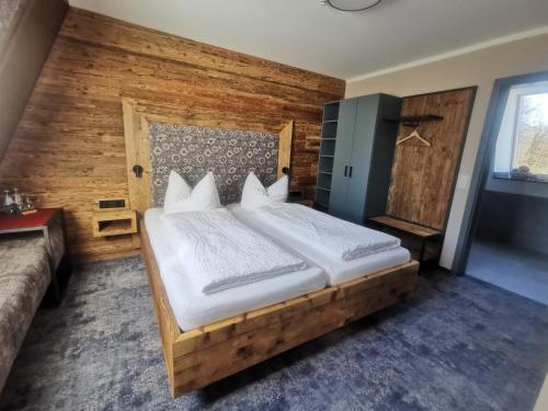 a bedroom with a large bed with a wooden wall at Schössersmühle in Eisenberg
