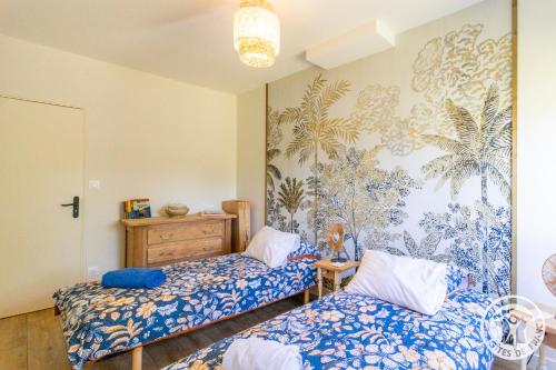 2 camas en una habitación con un mural en la pared en Gîte Ecrin de Verdure Jacuzzi et piscine, en Angrie