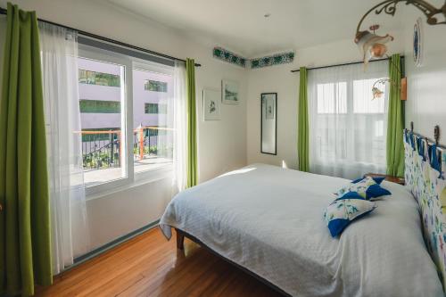 a bedroom with green curtains and a bed and a window at AYCA La Flora Hotel Boutique in Valparaíso