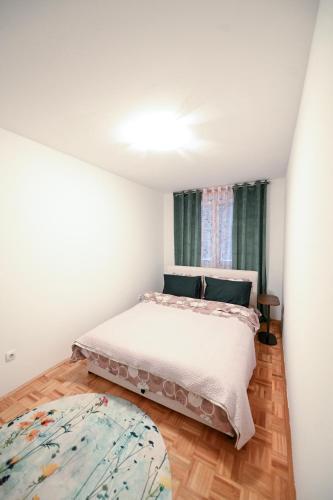 a white bedroom with a bed and a window at Olja in Sarajevo