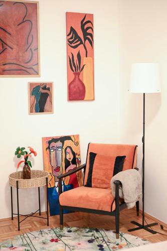 a living room with an orange chair and paintings at Olja in Sarajevo