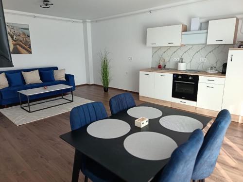 a living room with a table and blue chairs at B&B ApartHotel in Bistriţa