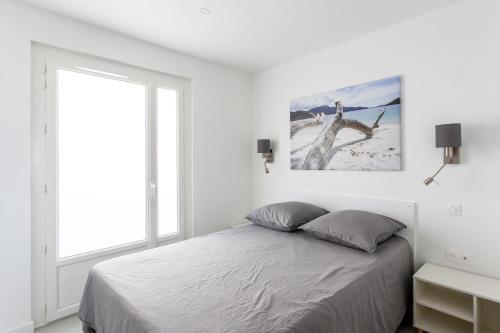 a white bedroom with a bed and a window at Sublime appartement face à la mer avec accès plage in Palavas-les-Flots