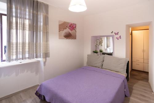 a bedroom with a purple bed and a window at Apartments Mihael in Baška