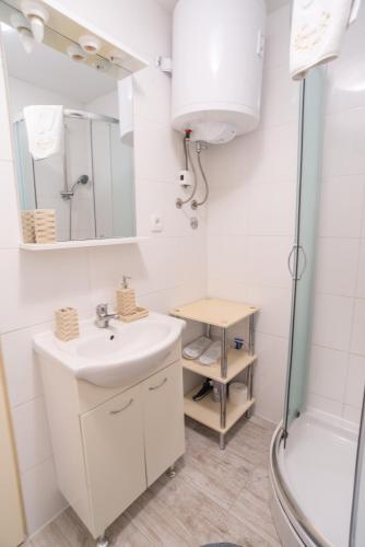 a white bathroom with a sink and a shower at Apartments Mihael in Baška