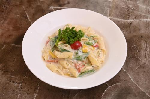 a white bowl of pasta with a garnishment at Park Eastern Hotel in Kolkata
