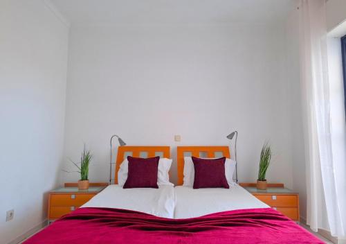 - une chambre avec un grand lit et des oreillers violets dans l'établissement Alltravel Vila Rosa apartment, à Portimão