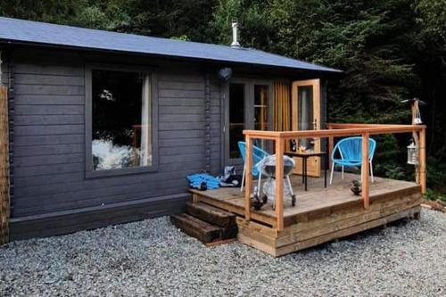 a cabin with two chairs and a table on a deck at Off Grid 1-Bed Cabin Pets Ok 20 mins to Dunoon in Blairmore