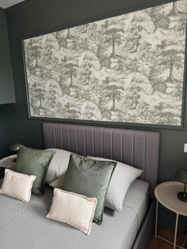 a bed with pillows and a large painting above it at F3 quartier historique, parking gratuit, vue Saône in Chalon-sur-Saône