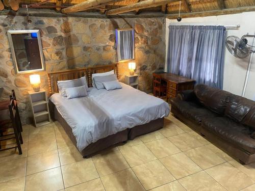 a bedroom with a large bed and a leather couch at Augustine Avenue Guest House in Ladysmith