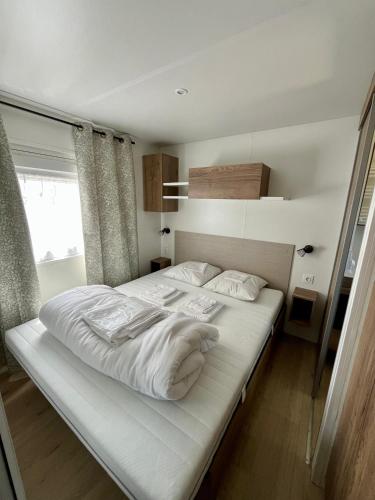 une chambre avec un lit avec des draps blancs et des oreillers dans l'établissement Bontempo Village camping 4 étoiles, à Piriac-sur-Mer