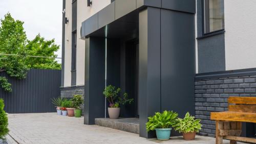 Un edificio negro con plantas en macetas en una acera. en SingKol Suites, en Bishkek