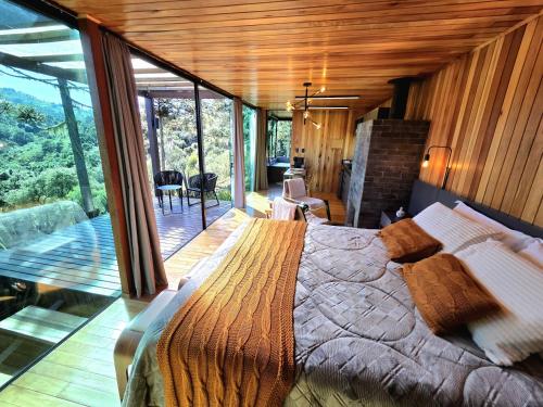 a bedroom with a large bed in a house at Cabanas Alto Padrão com Jacuzzi, Lareira e cachoeira exclusiva in Urupema