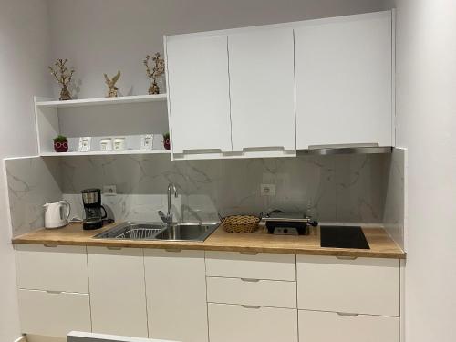 a kitchen with white cabinets and a sink at Seaside and mountain view apartment in Sarandë