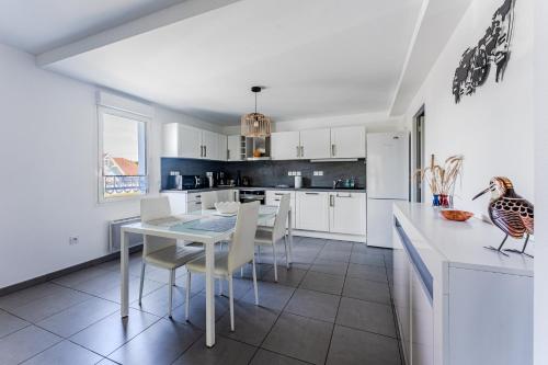a kitchen with white cabinets and a table and chairs at Appartement T3, Bassin D'arcachon in Andernos-les-Bains
