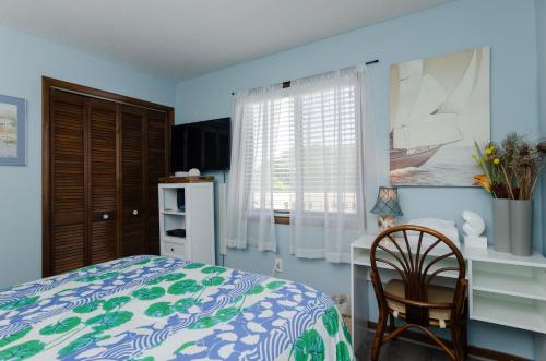 a bedroom with a bed and a desk and a chair at Waves N At by Bryant Real Estate in Kure Beach