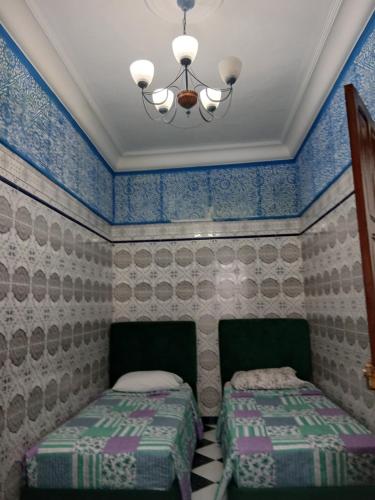 two beds in a room with blue and white wallpaper at Casa Medina Sanaa in Tetouan