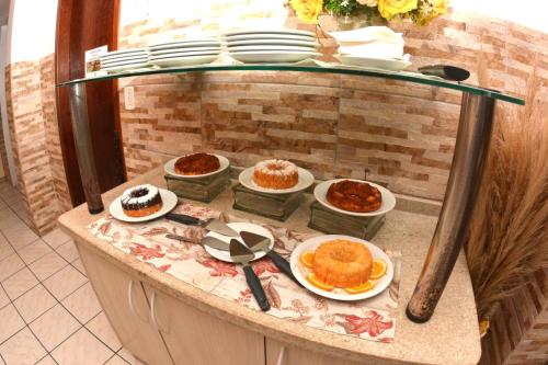 a buffet with cakes and desserts on plates on a counter at Pousada Don Alberto's in Florianópolis