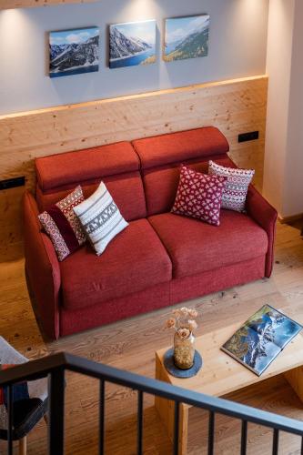 a living room with a red couch with pillows on it at Hotel Li Anta Rossa - Adults Only in Livigno
