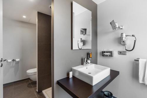 a white bathroom with a sink and a toilet at Relais de L'Empereur in Genappe