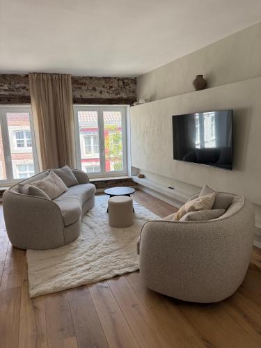 a living room with two couches and a flat screen tv at Historische bovenwoning Wyck in Maastricht
