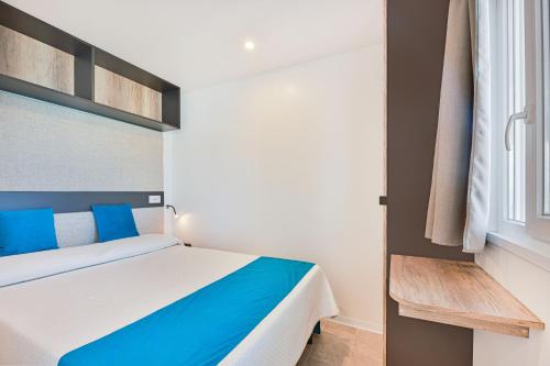 a bedroom with a blue and white bed and a window at Camping Village Le Calanchiole in Capoliveri