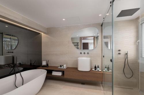 a bathroom with a tub and a sink and a mirror at 1bd Sv Beach Condo With Pool in Athens