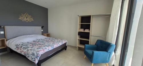 une chambre avec un lit et une chaise bleue dans l'établissement Villa REVA ,8 couchages, piscine entre terre et mer, à Nézignan-lʼÉvêque