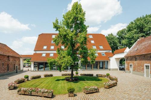 a tree in a courtyard in front of a building at Relais de L'Empereur in Genappe