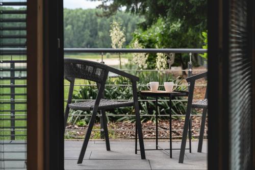 two chairs and a table with cups on a balcony at NOOQA - Villa RHEINLOFTS in Cologne