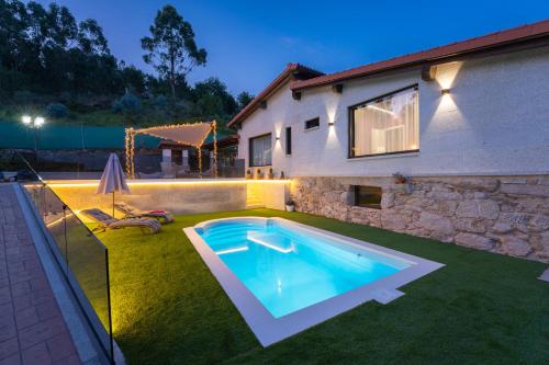 a swimming pool in a yard next to a house at Casa vacacional San Miguel in Maside