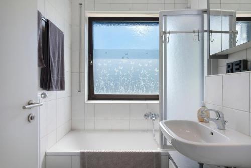 une salle de bain blanche avec un lavabo et une fenêtre dans l'établissement Ferienhaus Obergfell, 110 Qm, à Schönwald