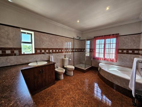 Villa Sant Andrea Boutique Luxury Villa في جوهانسبرغ: حمام مع دورتين مياه وحوض استحمام ومغسلة