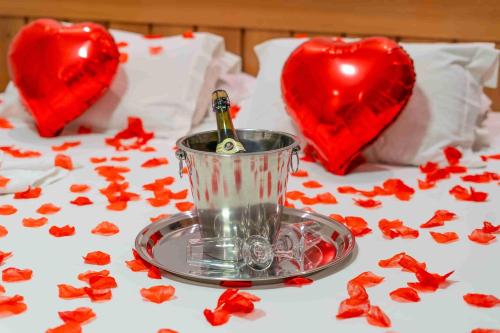 a table with a bottle of champagne on a bed with hearts at Pousada Nacional Inn Campos do Jordão in Campos do Jordão