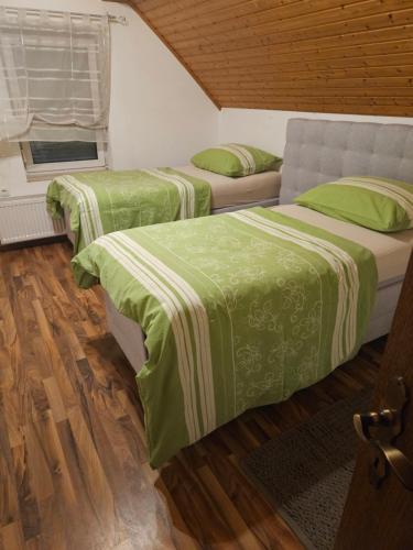 two beds with green sheets in a room at P Holding Apartments in Proleb