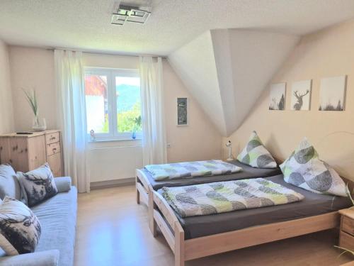 ein Schlafzimmer mit zwei Betten und einer Couch und einem Fenster in der Unterkunft Ferienhaus Seefried in Baiersbronn